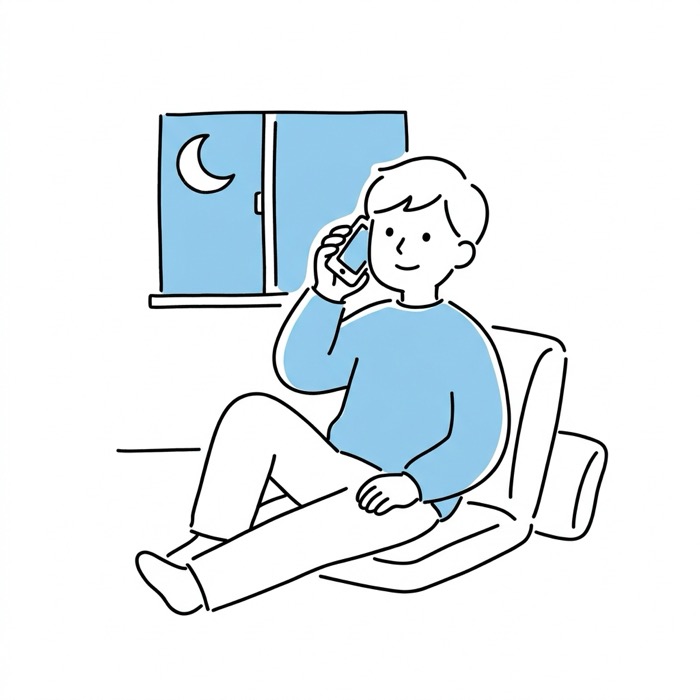 夜の部屋でスマホで話す男性